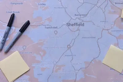 image shows a physical map of Sheffield with some marker pens and sticky notes laying atop of the map