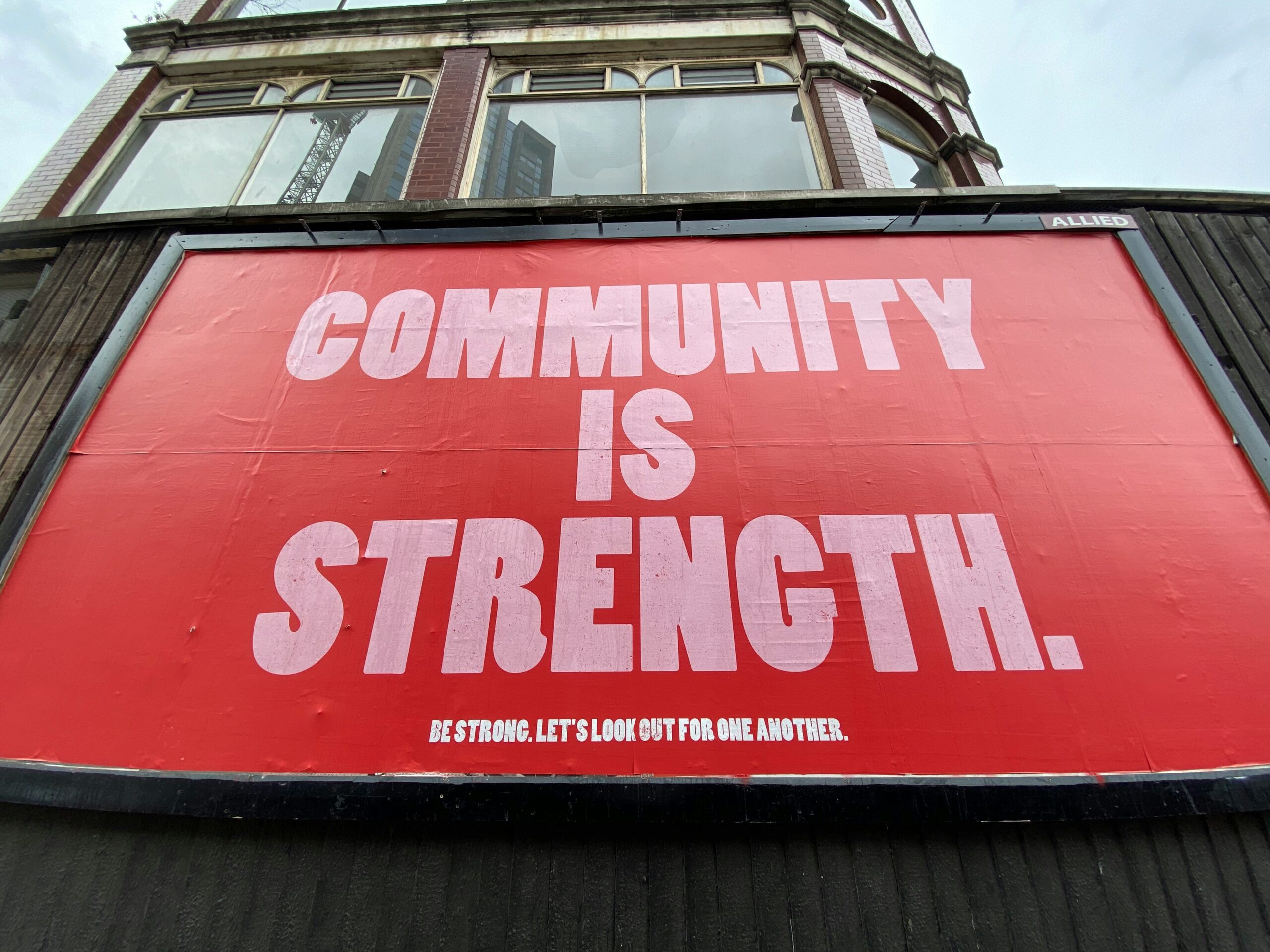 A large red billboard on the side of a building says 'Community is Strength'